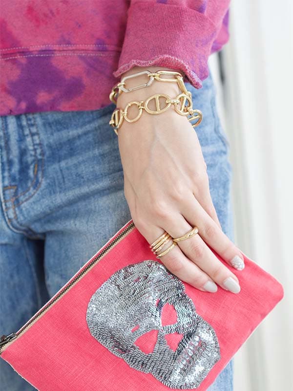 Close up of young woman’s hand holding pink purse modeling JL Rocks bracelets and rings